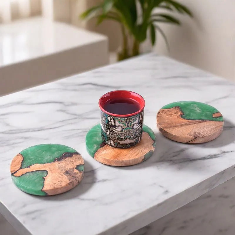 Round and square black and green resin coasters with wood texture for tea pots on a table.