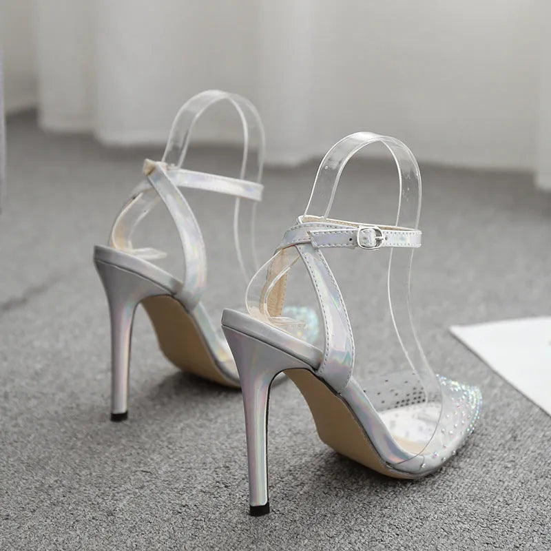 Women's pointed toe stiletto heel sandals with a glossy PVC upper and an ankle strap buckle.