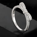 Silver-coloured bow-shaped ring with sparkling zircon crystals on a model's finger.