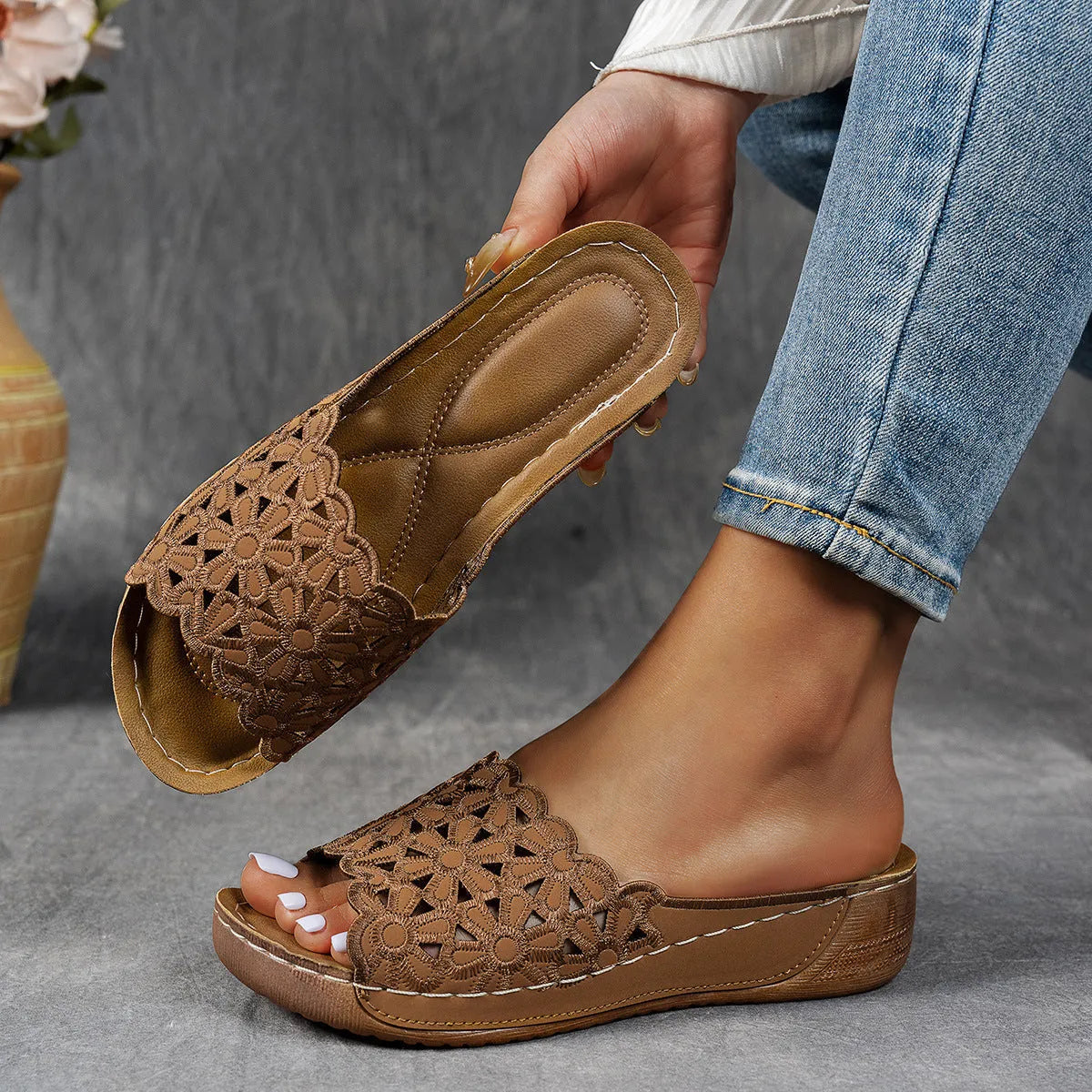 Women's black beach slippers with a flower cutout design on the upper and a wedge-style rubber sole.