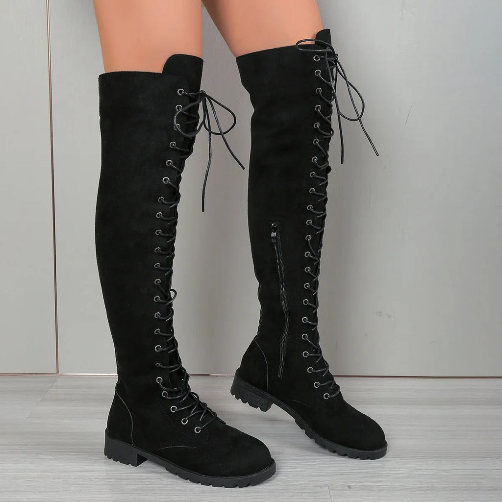 Black lace-up over the knee boots with round toe and flat rubber sole on a neutral background.