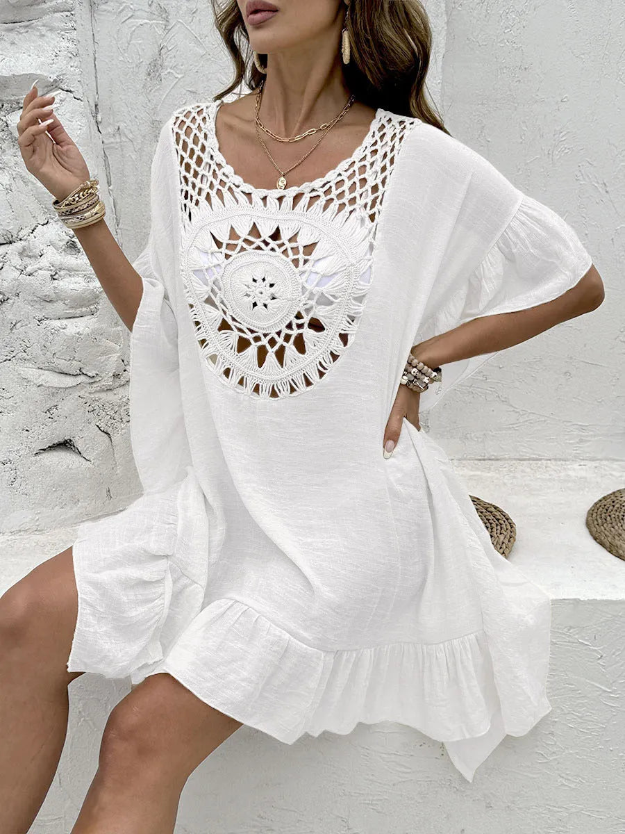 Woman wearing a knee-length apricot crochet patchwork dress with a tassel hem, a beach cover-up.