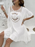 Woman wearing a knee-length apricot crochet patchwork dress with a tassel hem, a beach cover-up.