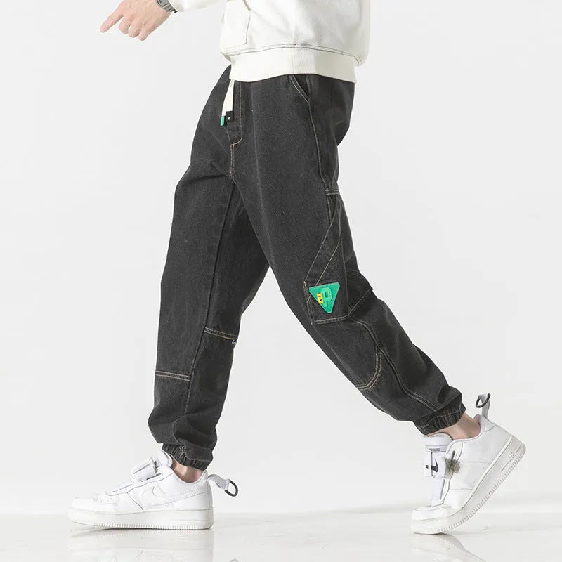 Men's loose-fit cotton tapered trousers in grey shown flat.