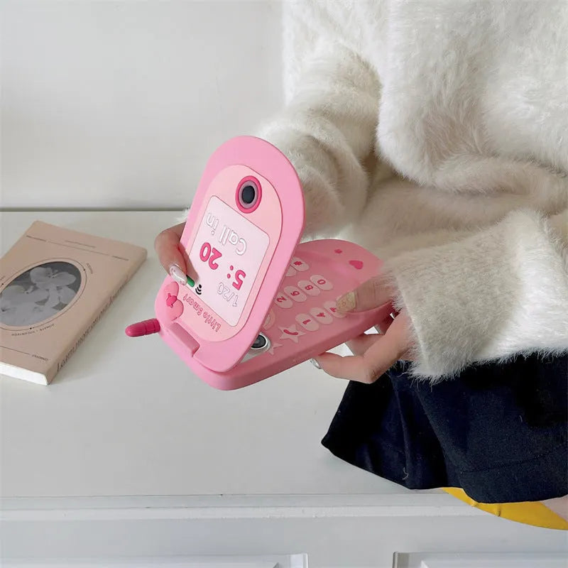 Pink silicone iPhone case shaped like a flip phone with a built-in mirror on the front.
