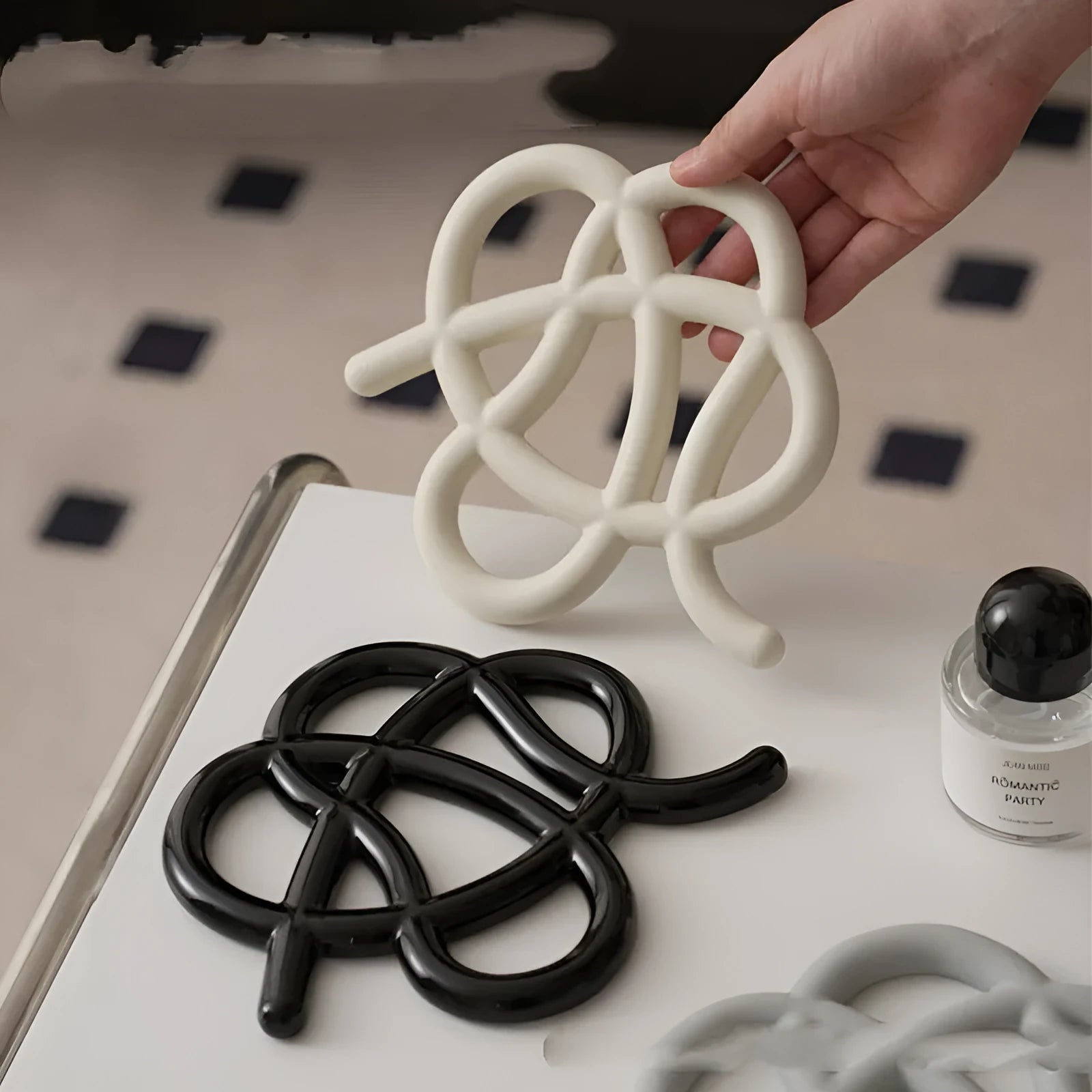 Irregular-shaped ceramic heat proof mat with hook and loop backing on a wooden table.