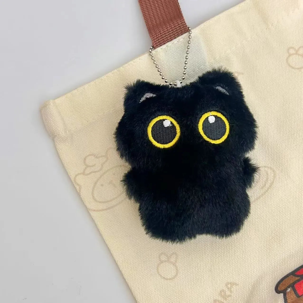 Cartoon big eye black cat doll plush with bead necklace as key decoration on a bag