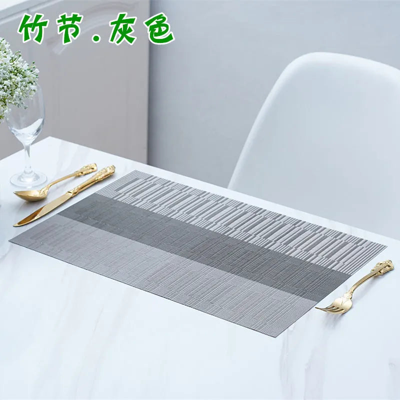 Modern non-slip PVC dish mat with gradient bamboo pattern in black, placed on a wooden dining table.