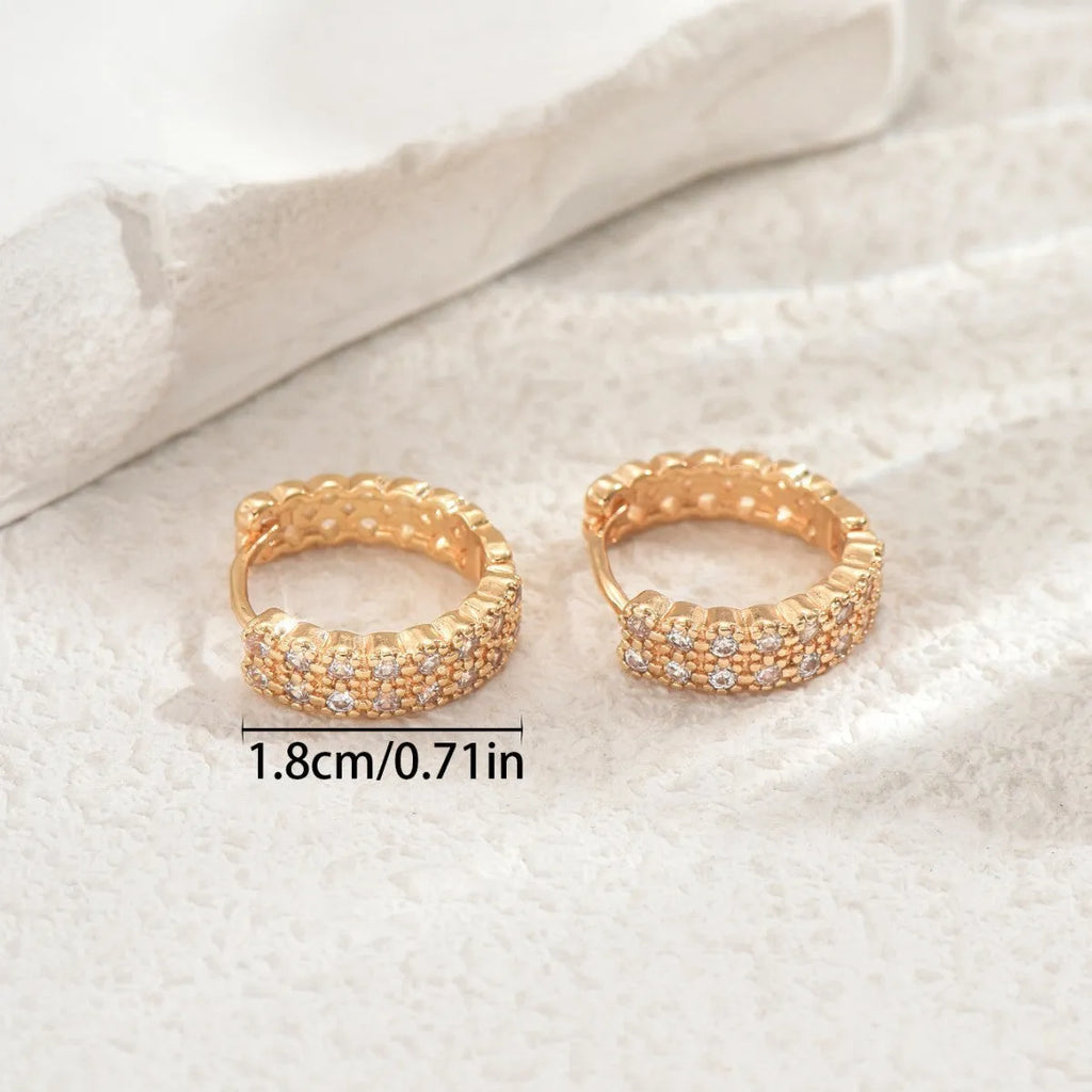 A pair of polished copper geometric ear studs featuring a thin ring with a small central dot on a white background.