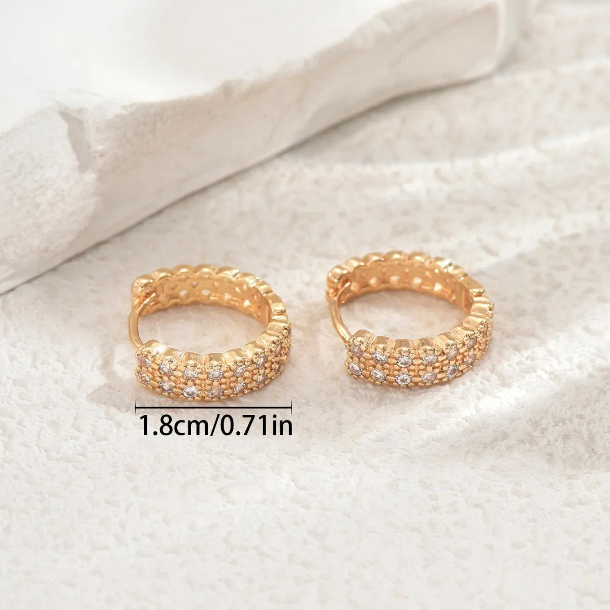 A pair of polished copper geometric ear studs featuring a thin ring with a small central dot on a white background.