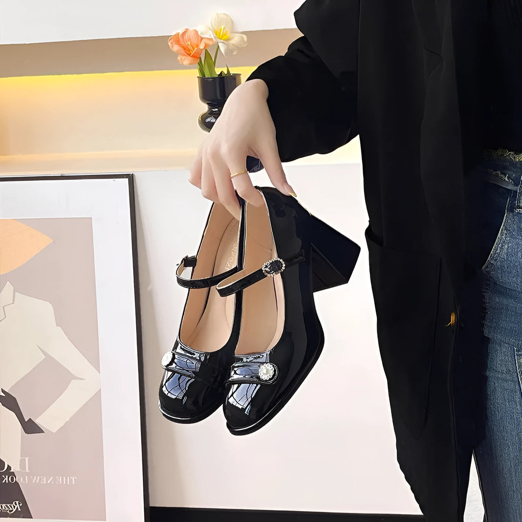 Women's black patent leather chunky heel shoes with a round toe and buckle fastening.