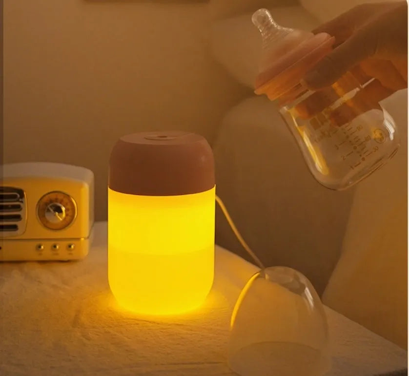 White cylindrical mini humidifier with USB cable and aromatherapy tray on a wooden desk.