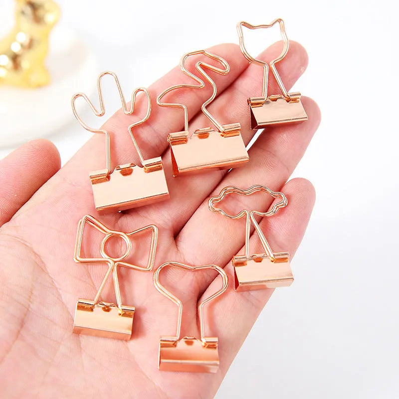 Gold metal stationery clip with a long tail, showing a decorative flamingo design.
