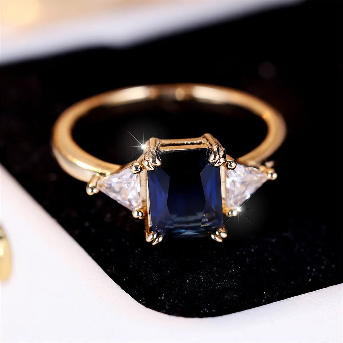 A gold sapphire blue rectangular copper ring for women on a jewellery display.