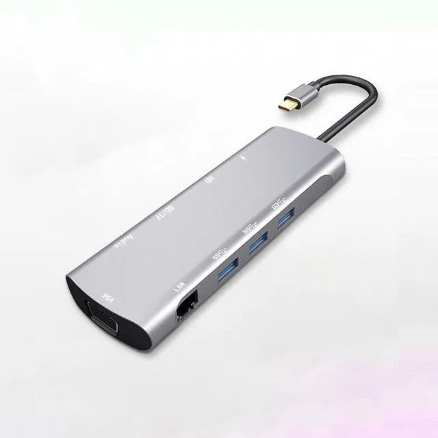 Grey aluminium USBC docking station with HDMI, VGA, USB ports and a short attached cable on a wooden desk
