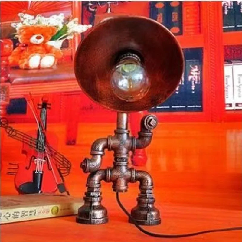 Industrial retro style iron pipe table lamp with water pipe robot design on a desk.