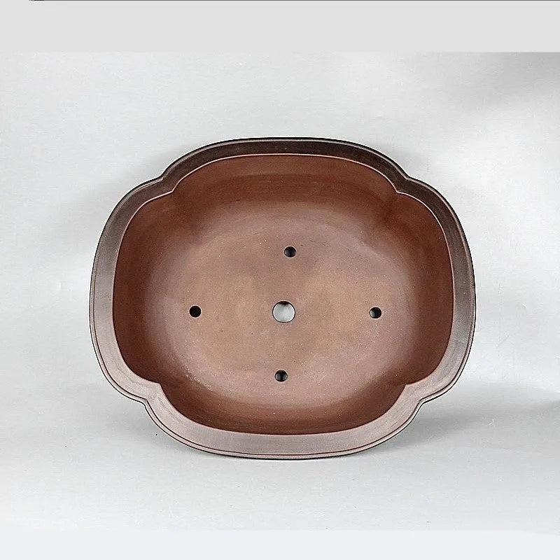 Handmade antique crabapple shaped purple clay flowerpot on a wooden floor.
