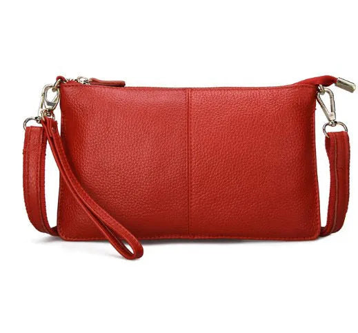 A small lady's cowhide slant handbag in claret colour, showing the hand strap and long shoulder strap.