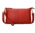 A small lady's cowhide slant handbag in claret colour, showing the hand strap and long shoulder strap.