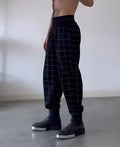 Men's plaid trousers with an apron-style front panel, shown on a model.