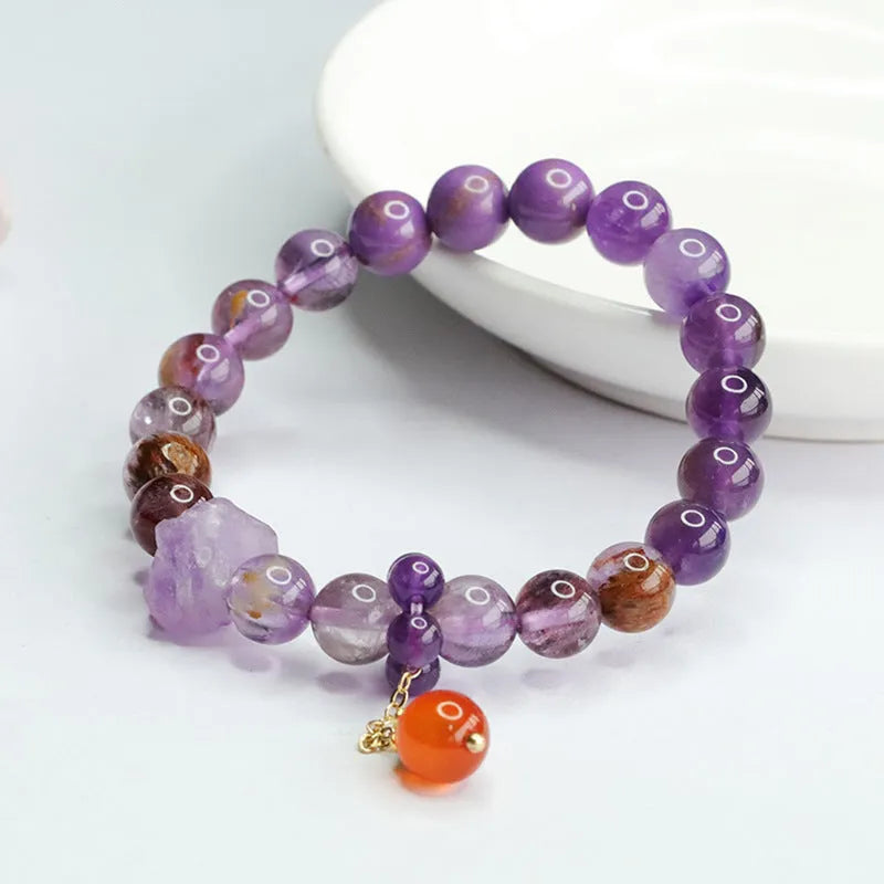 Nine purple fire amethyst and red agate Mori-style crystal bracelet on a wrist.