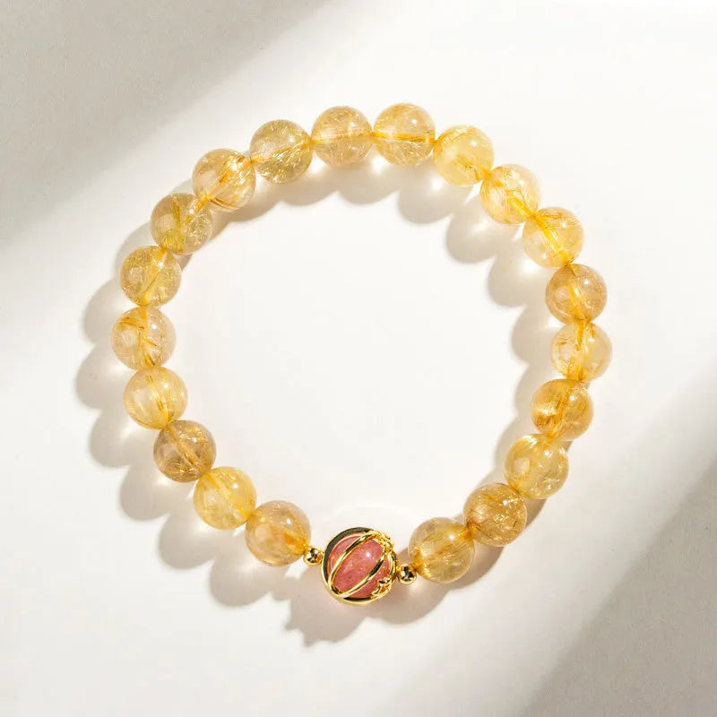 Citrine gold rutilated quartz crystal bracelet with diamond-cut beads on a wrist.