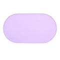 Green silicone cat feeding mat with raised edge containing a food bowl and scattered kibble on a kitchen floor.