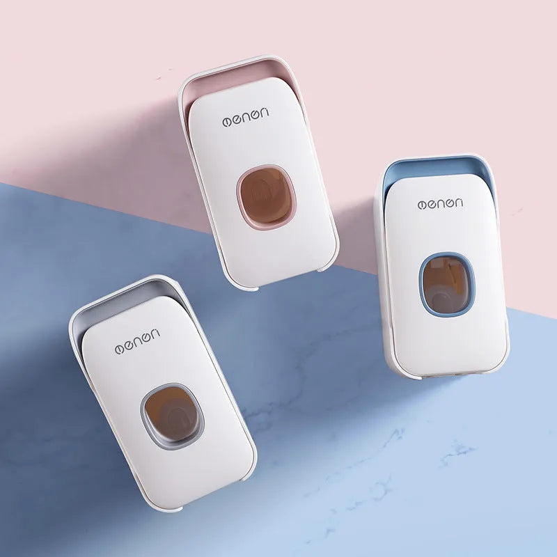 Automatic toothpaste dispenser in grey, blue, and pink colours on a bathroom countertop.