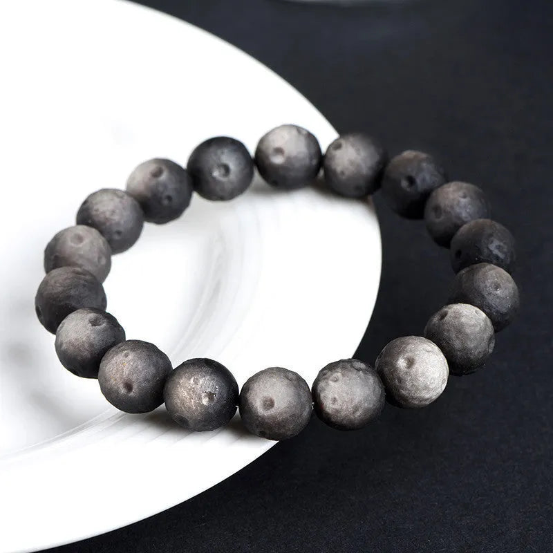 Unisex natural obsidian crater ball bracelet in silver stone meteorite colour with textured beads.