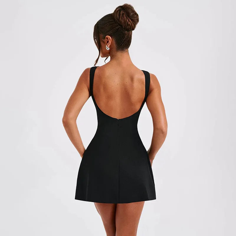 A woman wearing a black backless sling dress with a high waist and short skirt.