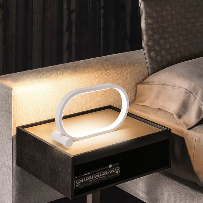 USB plug-in oval acrylic touch control night light with metal base, black finish, on a bedside table