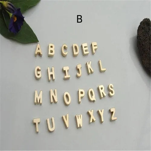 Gold alloy peach heart-shaped pendant featuring a single raised letter, shown from the front.
