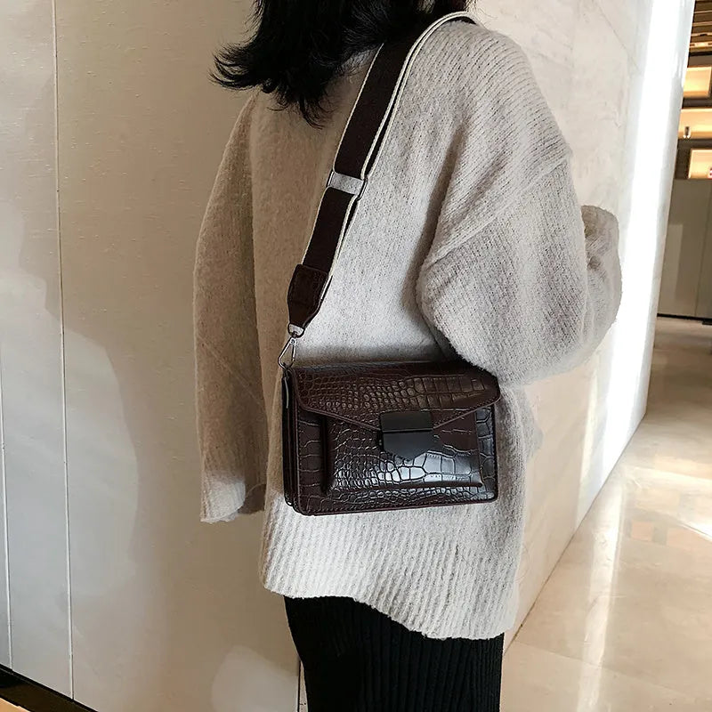 Vintage style black crossbody bag with an adjustable shoulder strap on a mannequin.
