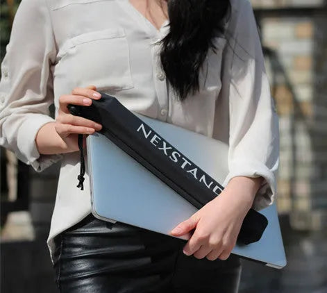 Black folding portable laptop stand with reinforced nylon construction shown unfolded beside laptop