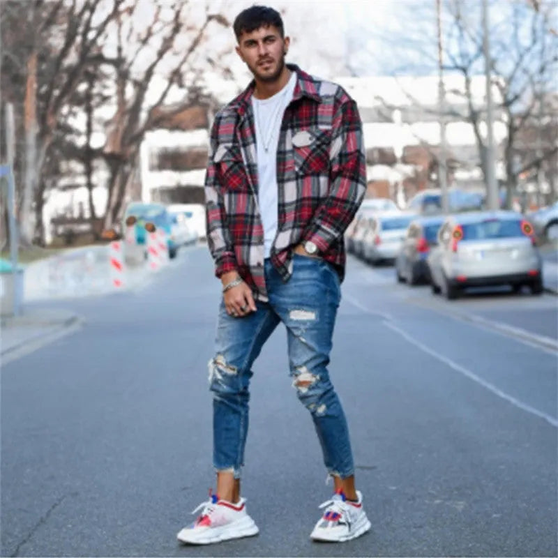 Men's deep blue cotton jeans with distressed hole detailing laid flat.