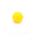 Bright blue, green, pink, and yellow spiked squeaky dog toy balls on a grass lawn.