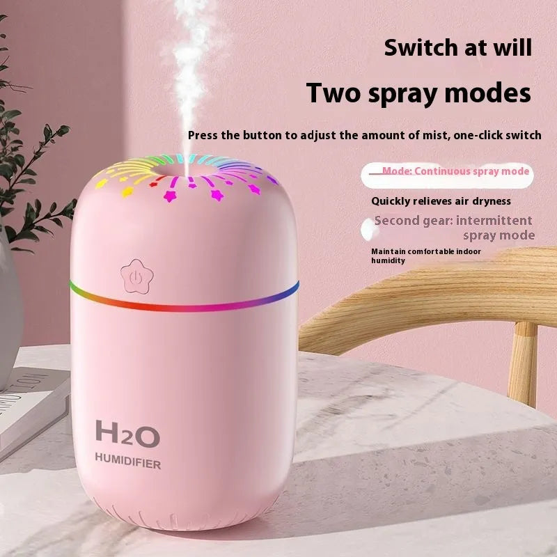 Small white USB humidifier with water tank on a wooden desk next to a laptop.