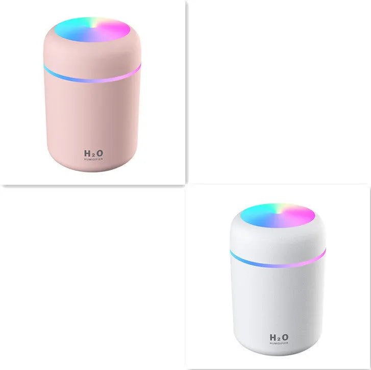 Pink USB mini humidifier with LED lights on wooden desk beside laptop