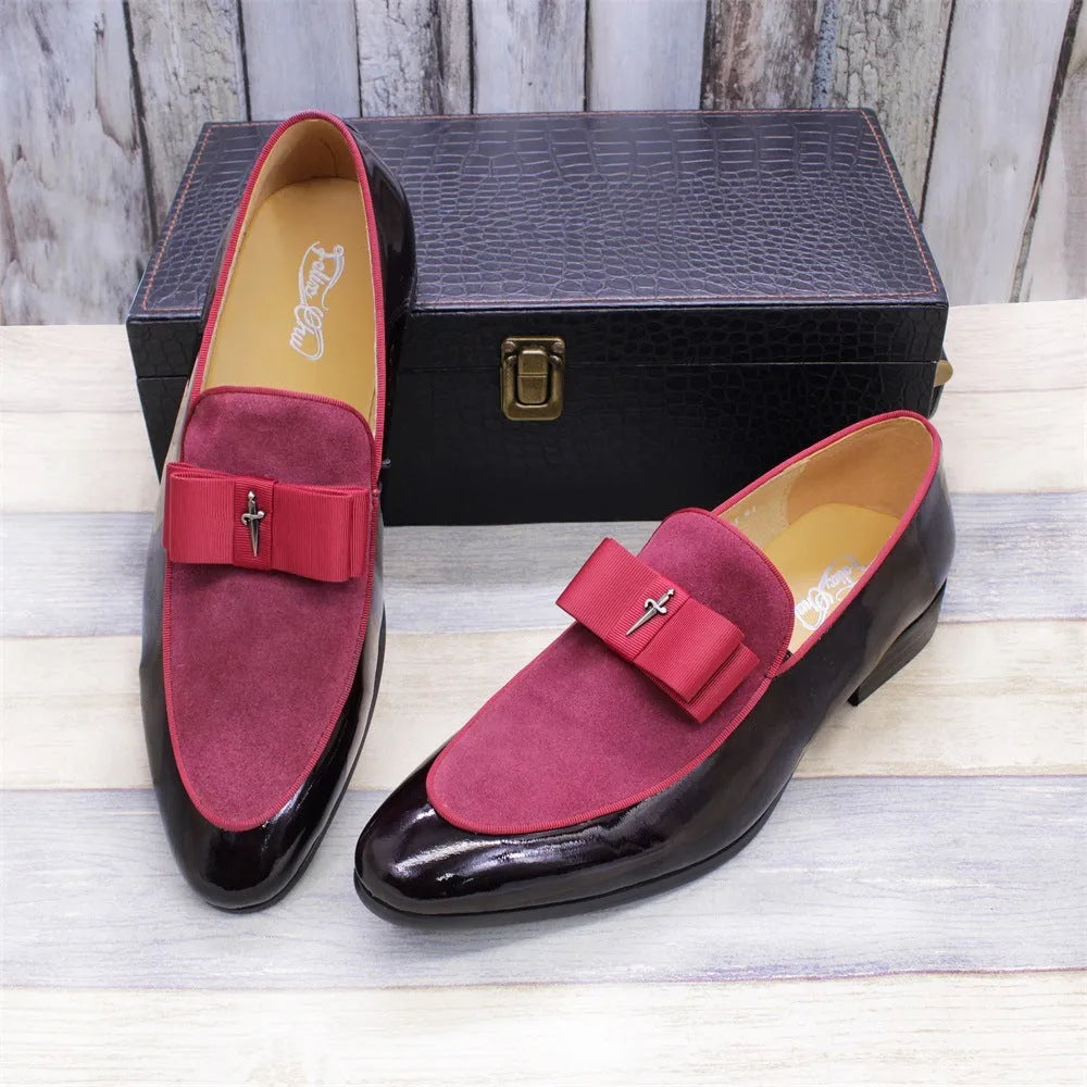Men's black tassel loafers with matte and glossy patent leather uppers and a rubber sole, shown on a wooden surface.