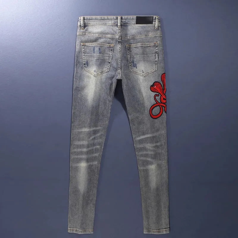 Old colour slim fit jeans with washed-out finish, patch details, and embroidery on cotton fabric.