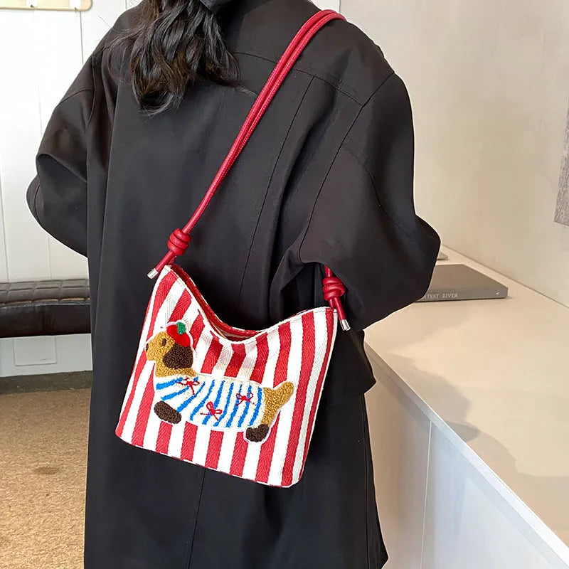 Cartoon sausage dog bucket bag in polyester with canvas lining, soft crossbody shape and single strap.