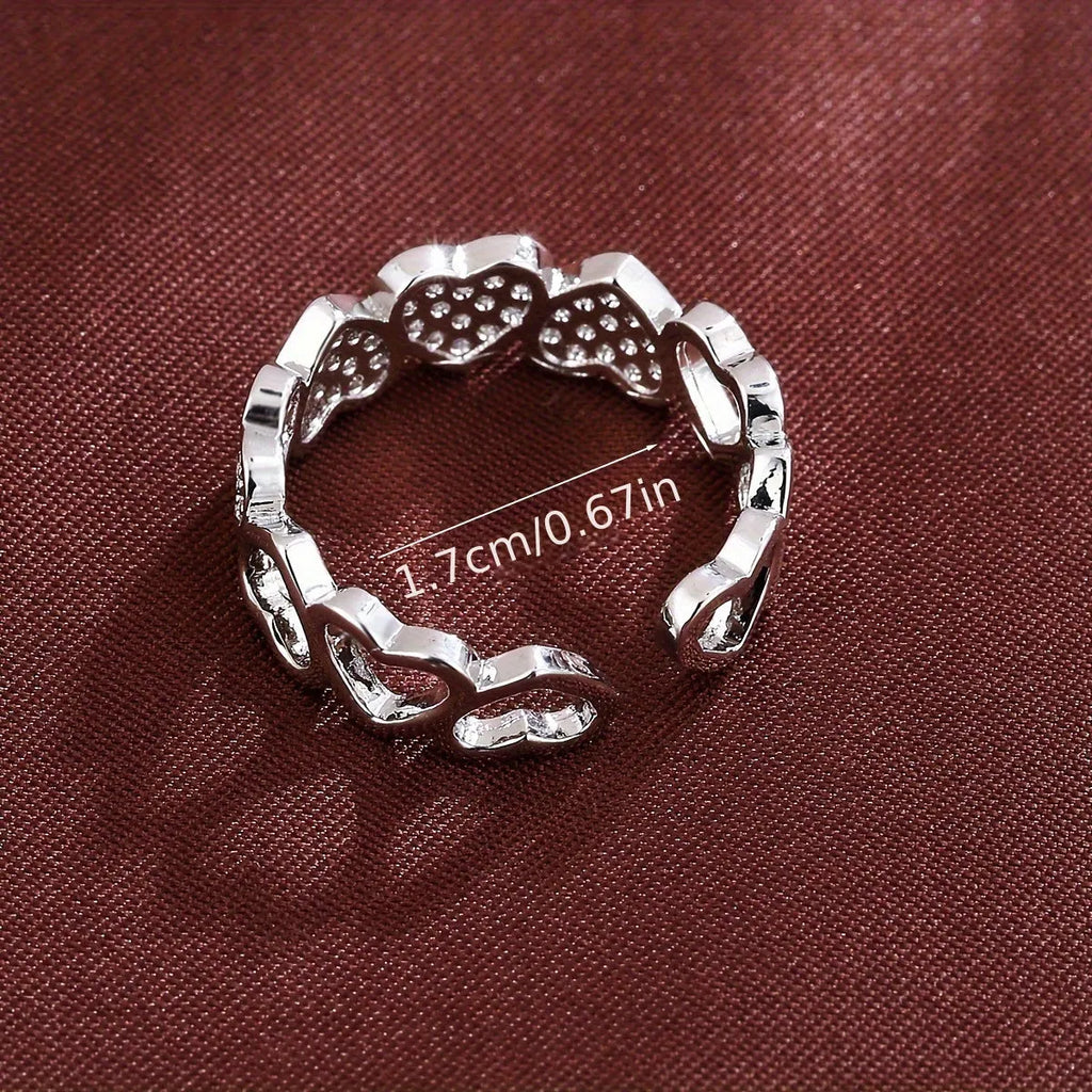 Geometric adjustable love heart ring with diamond-cut facets in gold tone on a wooden surface.