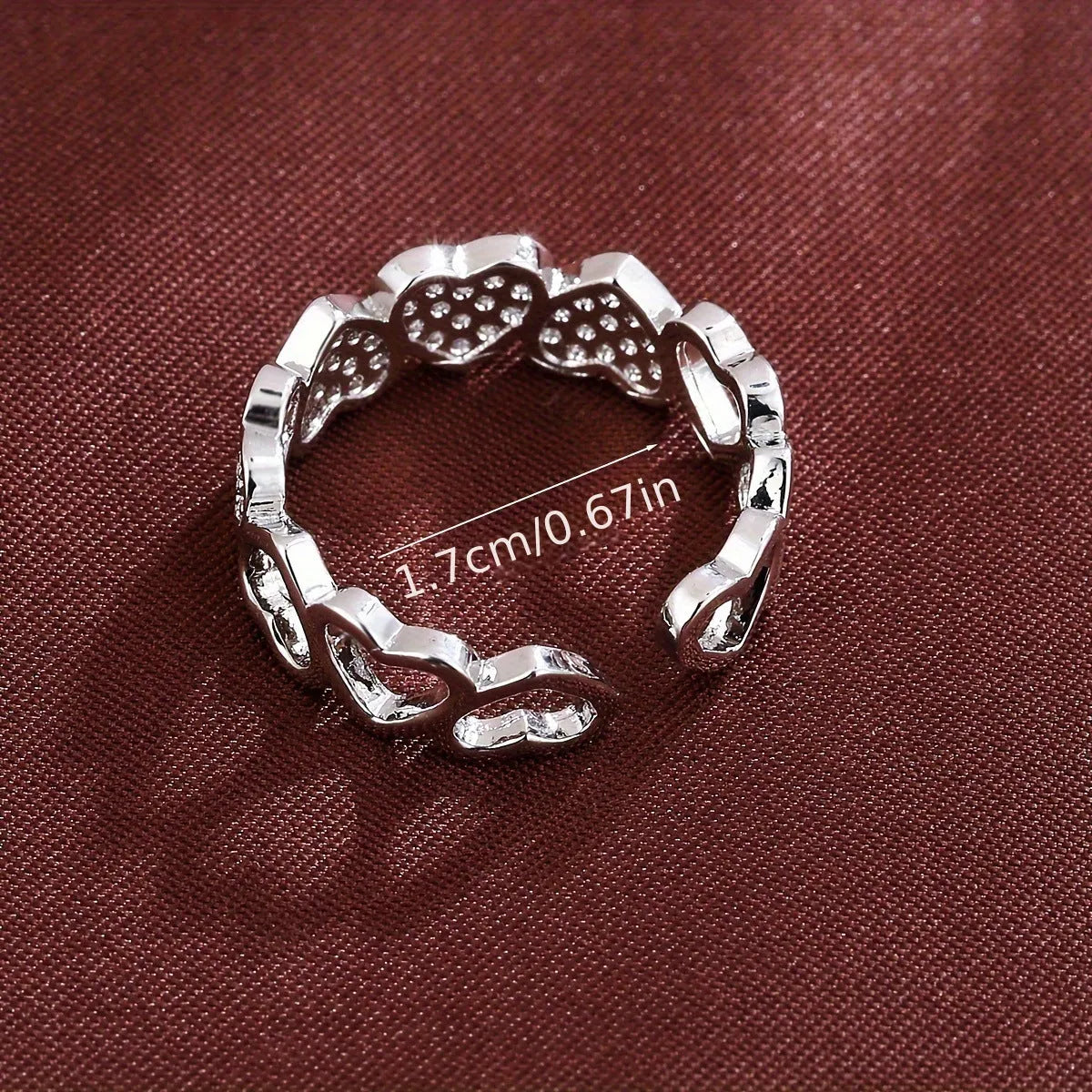 Geometric adjustable love heart ring with diamond-cut facets in gold tone on a wooden surface.