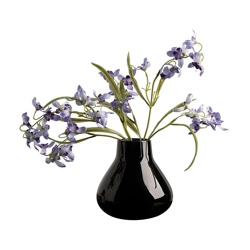 Modern round belly ceramic vase with coloured glaze, shown in black and white, some with artificial flowers.