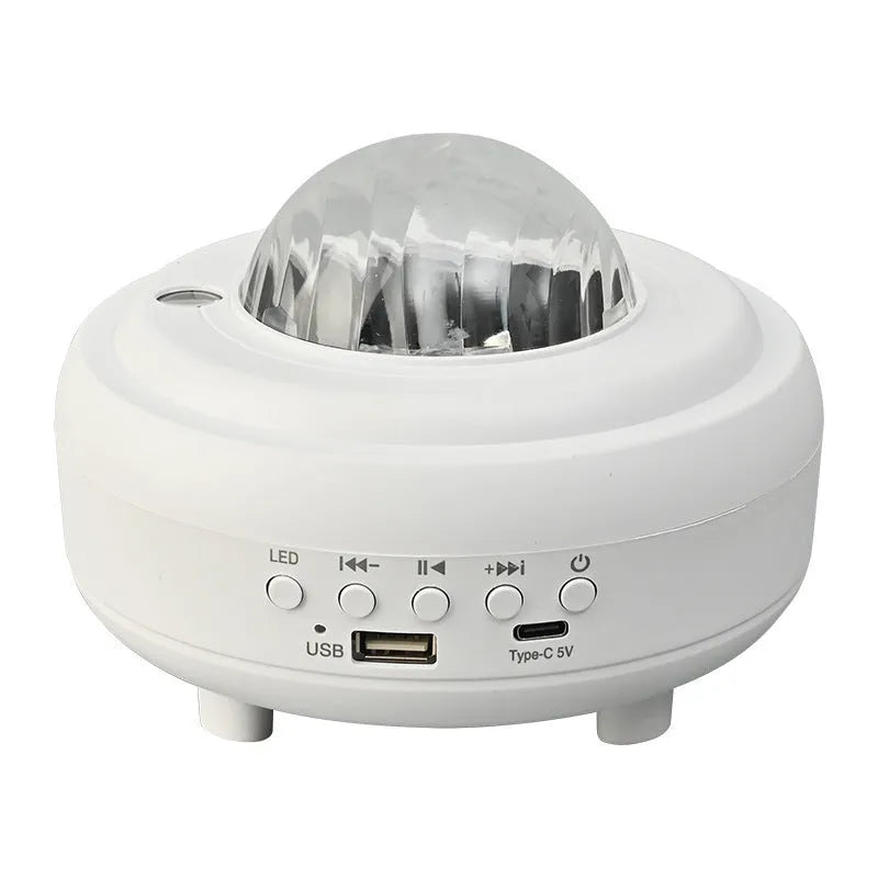 White and black galaxy star projector night light with Bluetooth speaker on a surface.