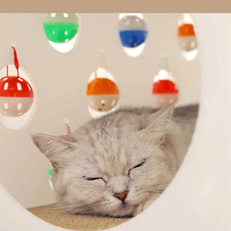 Durable plastic cat scratch board with an attached tunnel and a dangling bell ball toy on a neutral carpet.