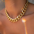 Gold women's thick link chain necklace with a 6cm drop pendant on a model.