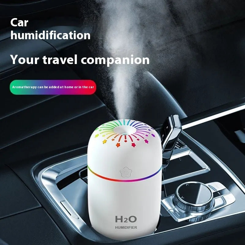 Small white USB humidifier with water tank on a wooden desk next to a laptop.