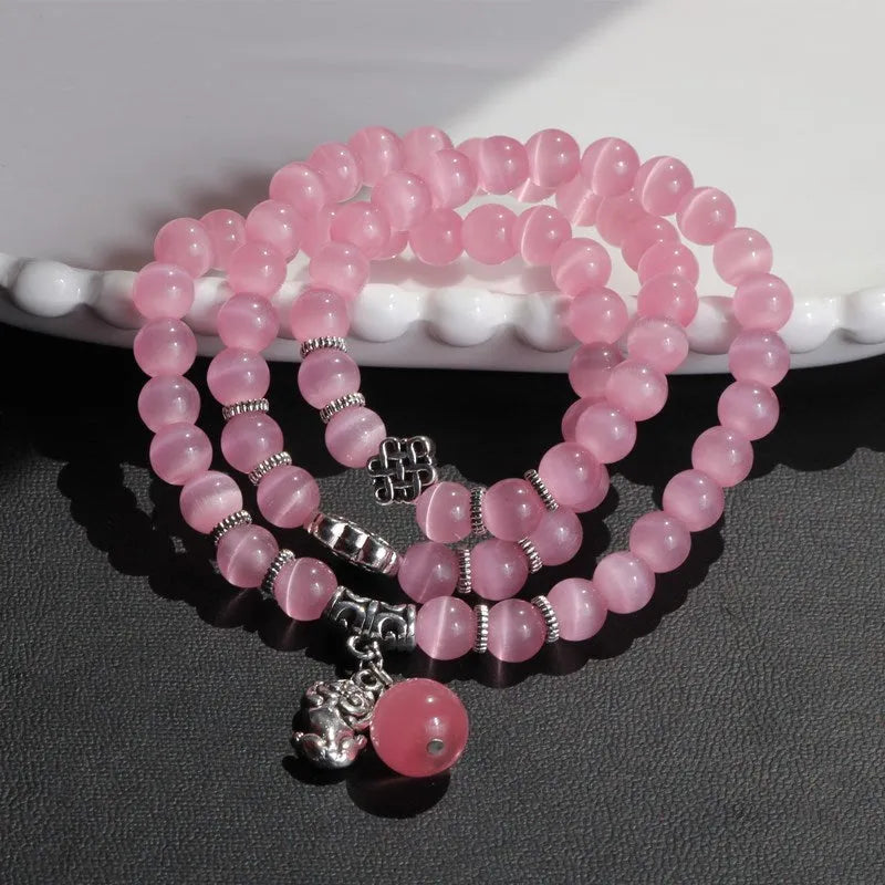 Women's opal bracelet with three interlocking rings, a Lucky Cat charm, and geometric stones in various colours.