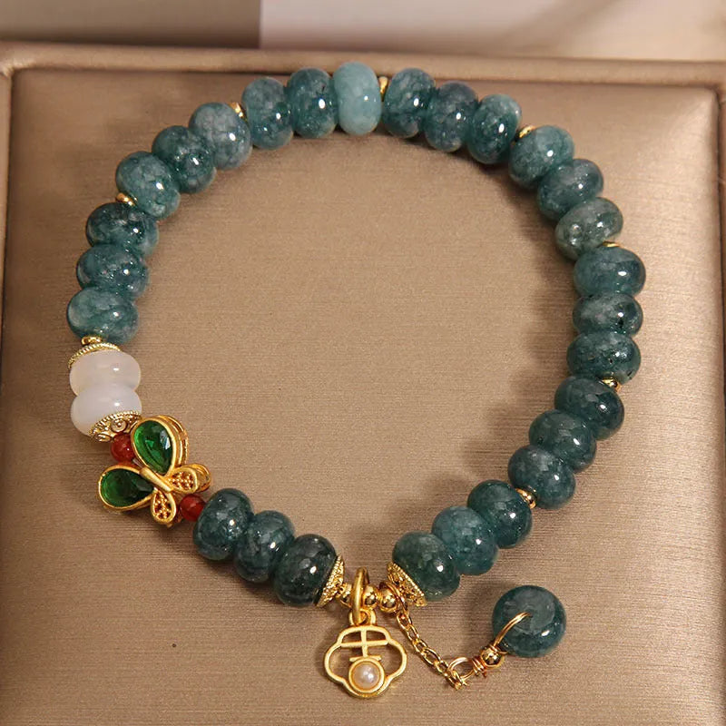 Blue water jade bead bracelet with white agate abacus beads and a butterfly charm.
